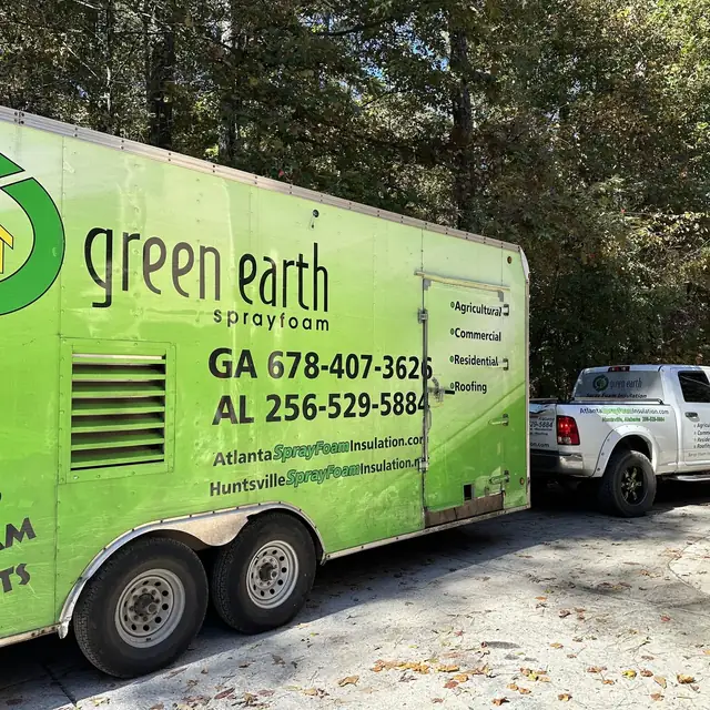 The Green Earth spray foam trailer and work truck parked on site at a wooded property.