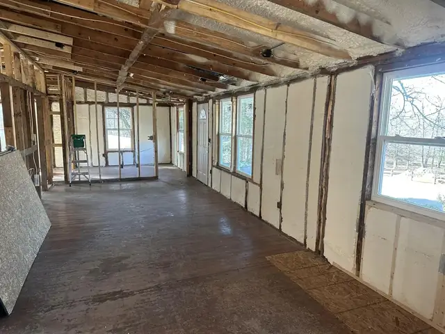 Interior of a gutted house with spray foam applied between the wall studs around the windows.