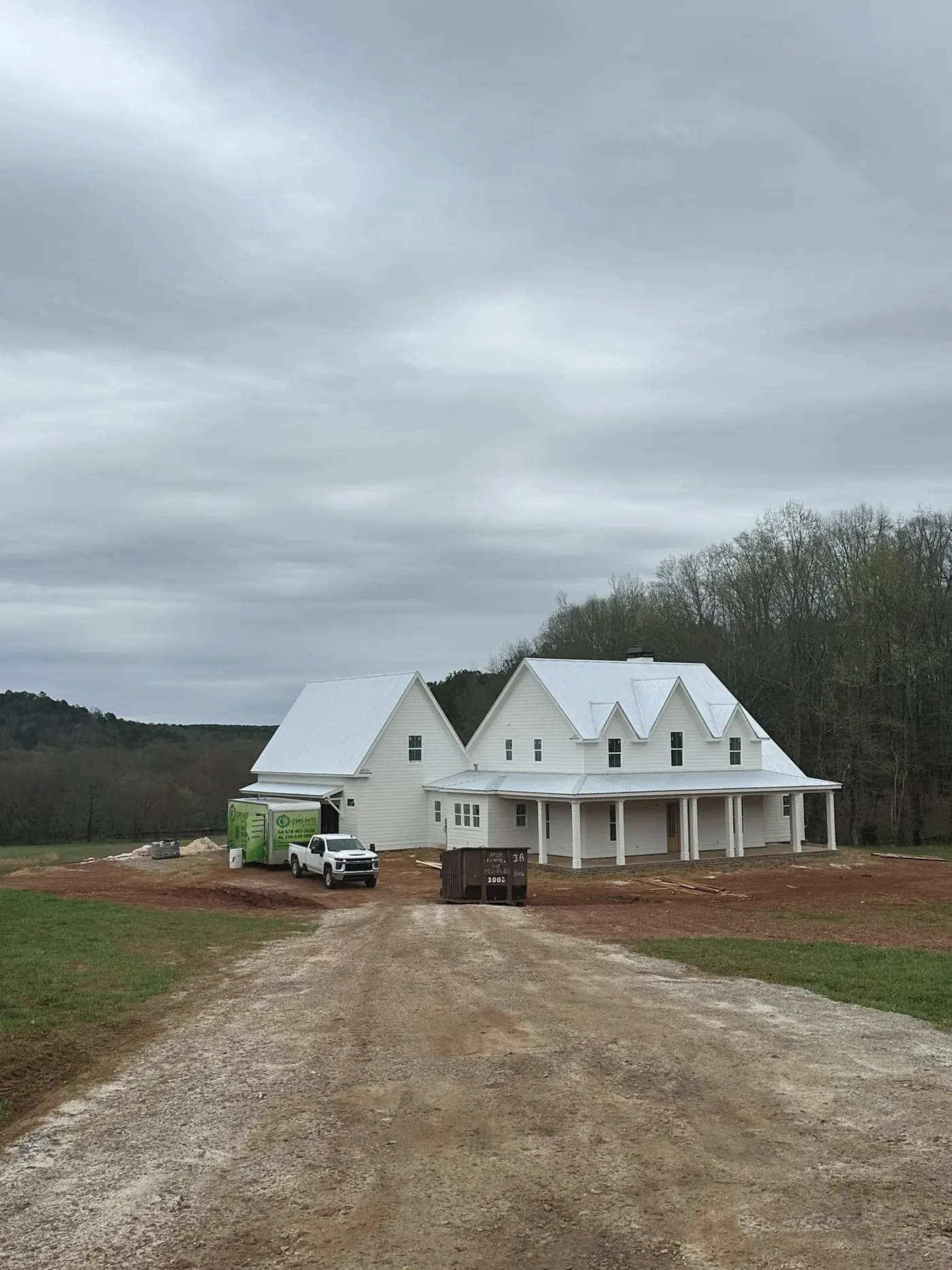 White farmhouse on a rural lot with the Green Earth truck and trailer parked alongside during a job.