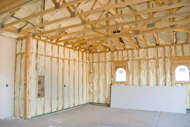 Garage interior with spray foam applied across the walls and ceiling joists before drywall.